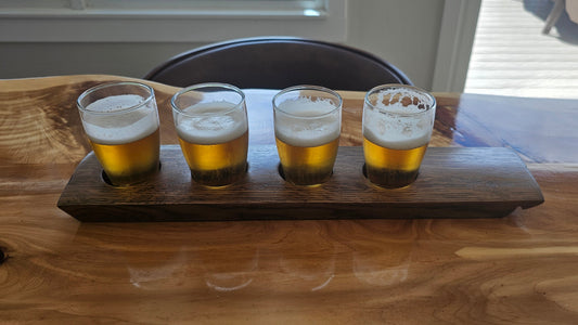 Four glasses of beer on a wooden tray with a blurred background