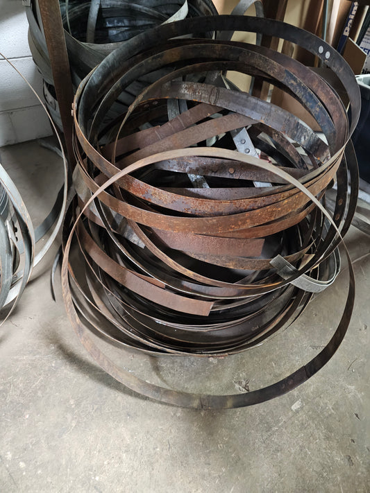 Stack of worn metal belts on a concrete floor