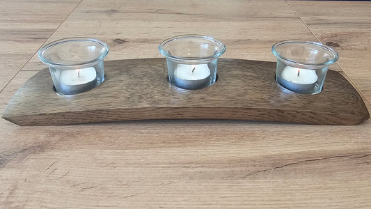 Wooden candle holder with three glass holders on a wooden surface