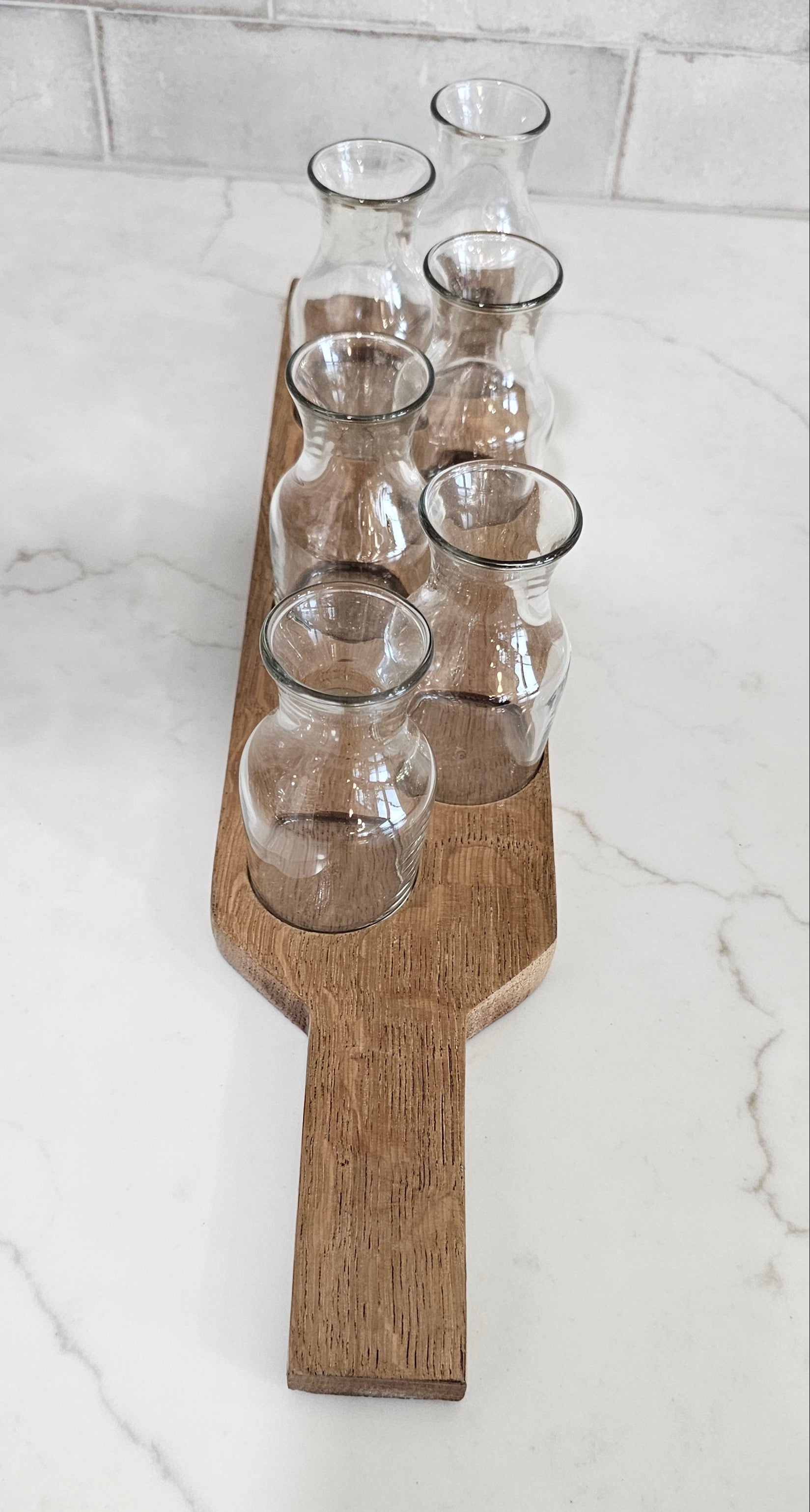 Wooden wine glass holder with six clear glasses on a marble surface