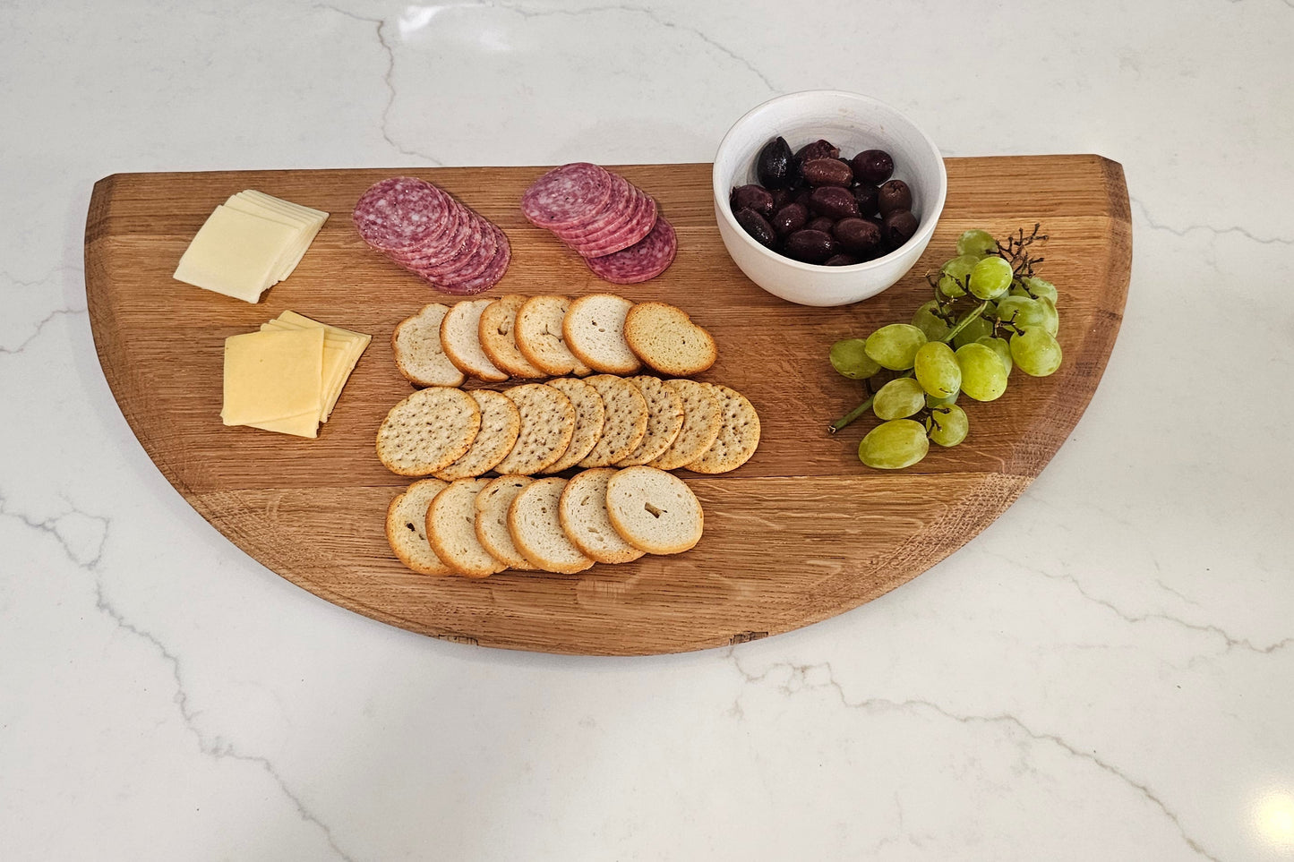 Wooden cutting board with assorted snacks on a white countertop