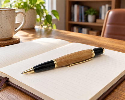 24K Gold Wall Street Executive Pen – Whiskey Barrel Wood Luxury Writing Instrument in naturally resting diagonally across the lower blank page of an open cream notebo.