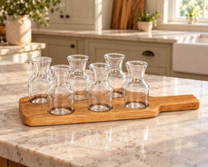Six mini wine carafes on a reclaimed oak barrel-head flight board on a kitchen island.