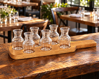 Six mini carafes on the reclaimed oak flight board at a restaurant service counter.