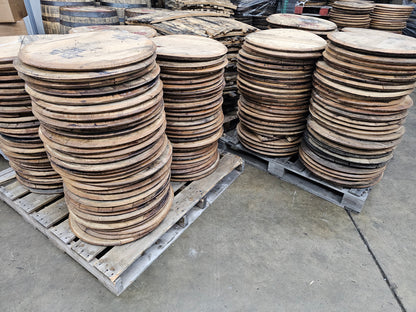 Stacks of authentic reclaimed bourbon barrel heads showing natural variation in the raw wood.