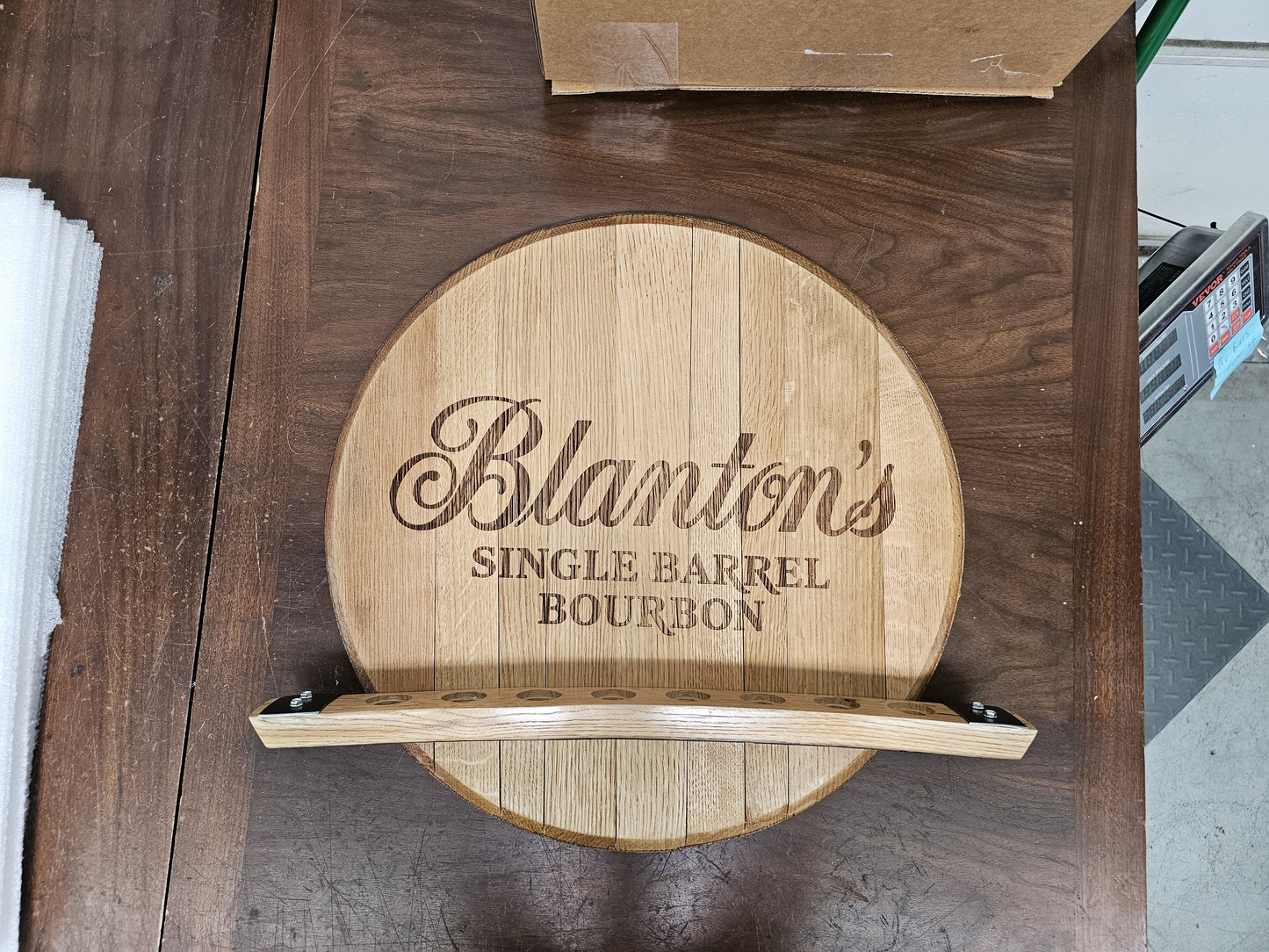 Front view of the empty Blanton's barrel head wall display with eight stopper openings.