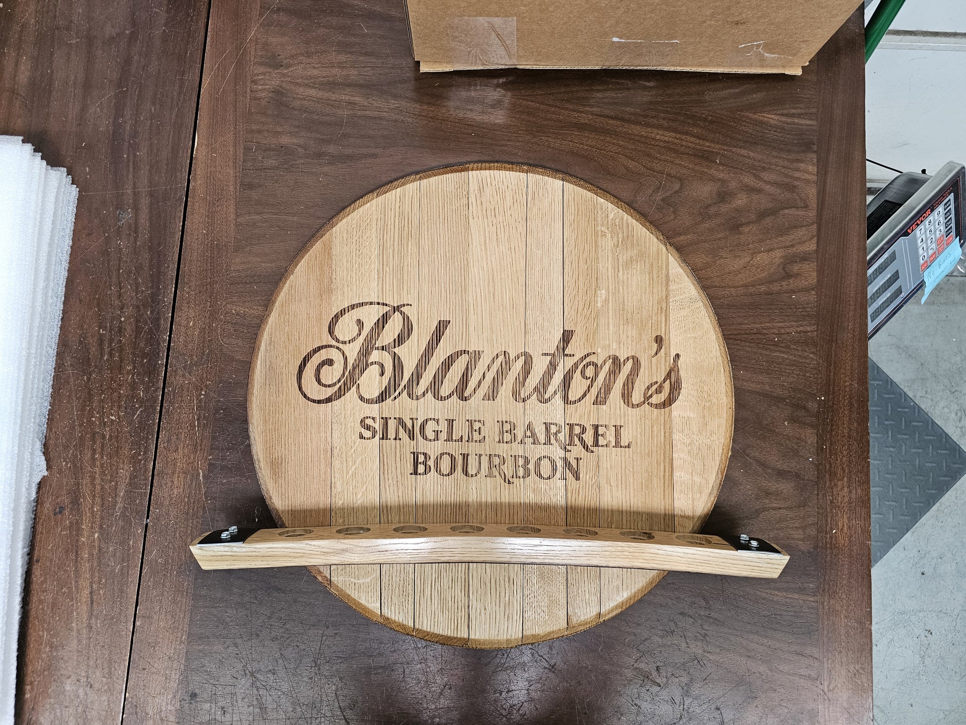 Front view of the empty Blanton's barrel head wall display with eight stopper openings.