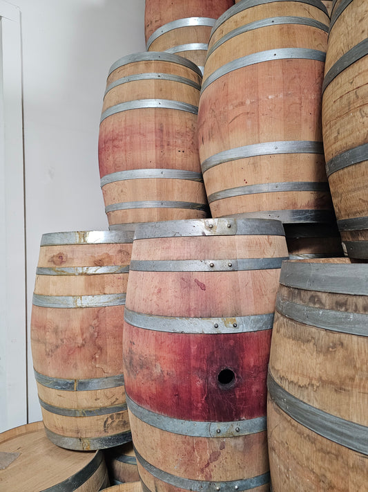 Stack of wooden wine barrels with metal bands on a white background