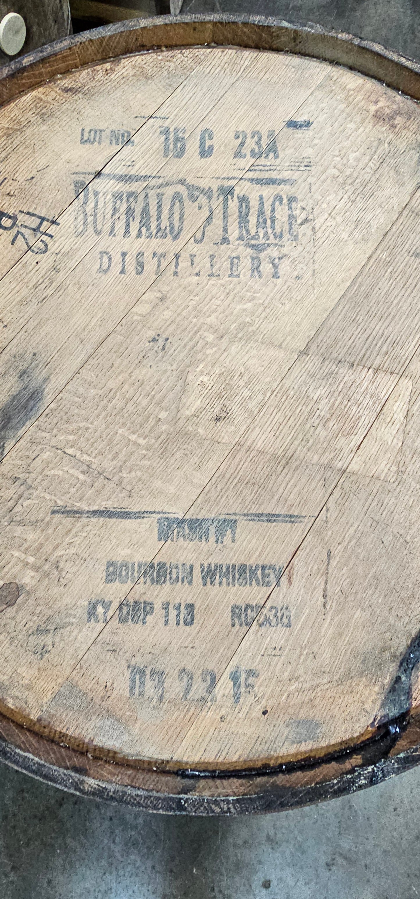 Close-up of a wooden barrel with branding and text on a concrete surface