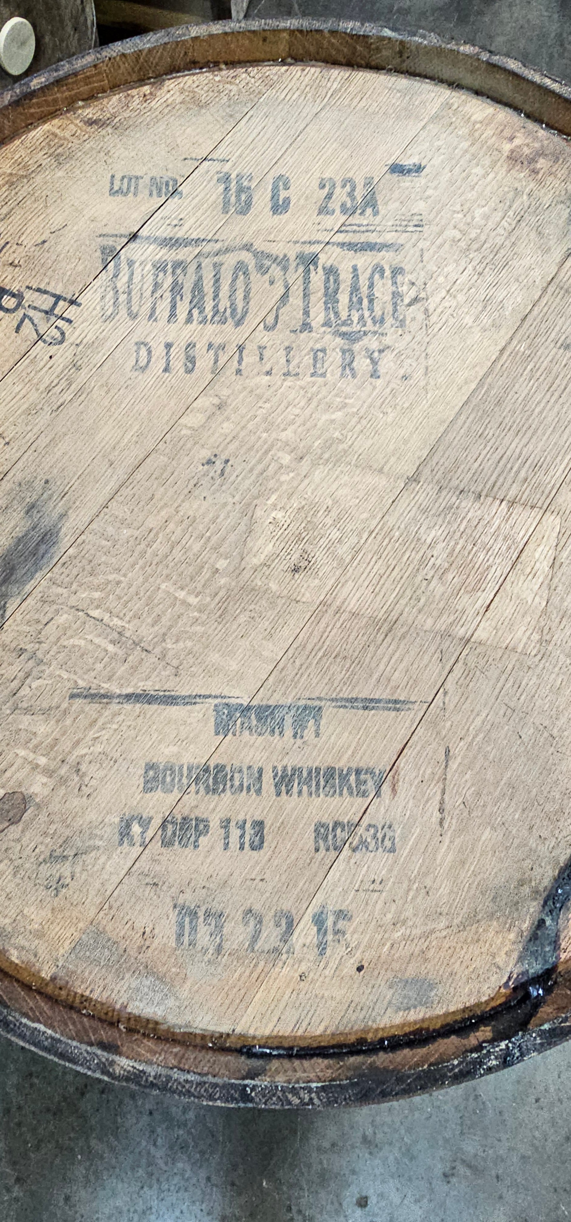 Close-up of a wooden barrel with branding and text on a concrete surface