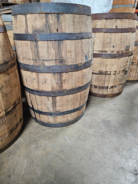 Three wooden barrels with metal bands on a concrete floor